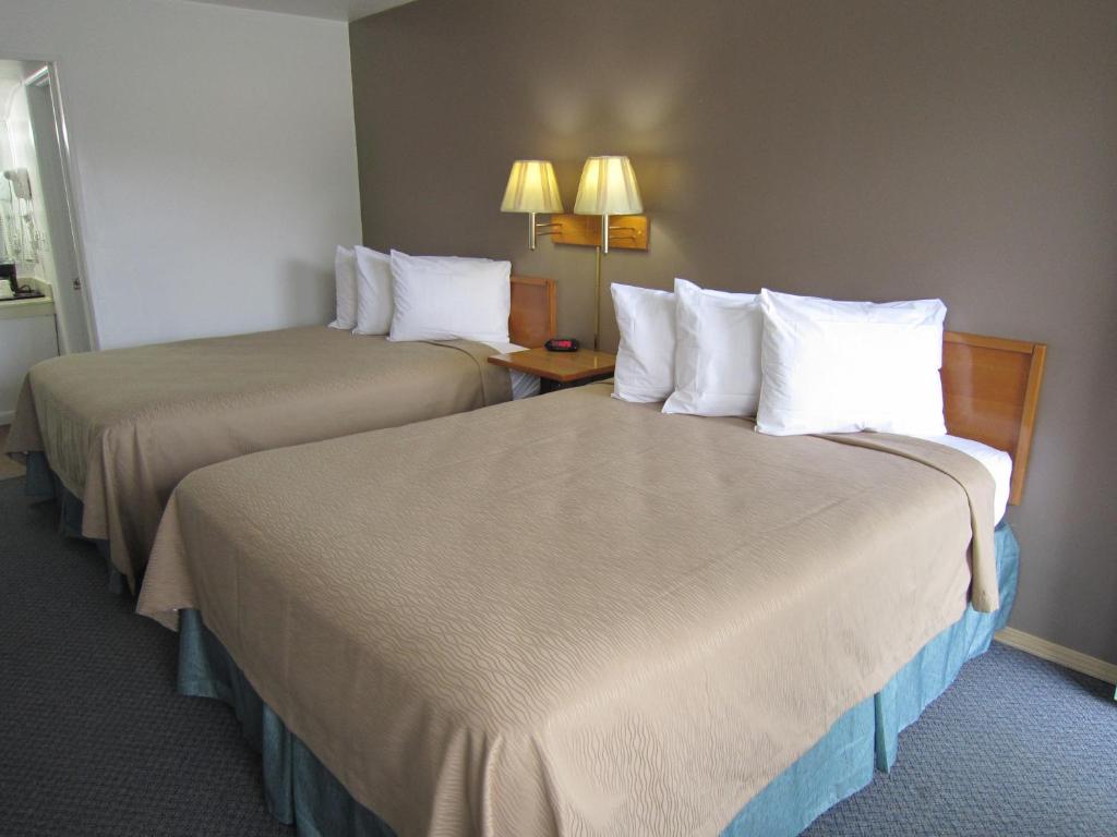 two beds in a hotel room with white pillows at Cassville Budget Inn in Cassville