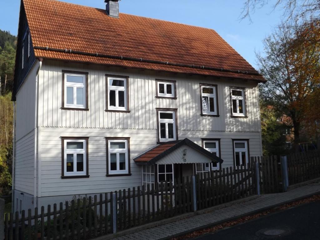 Casa blanca con techo marrón y valla en Landhaus Lautenthal, en Lautenthal