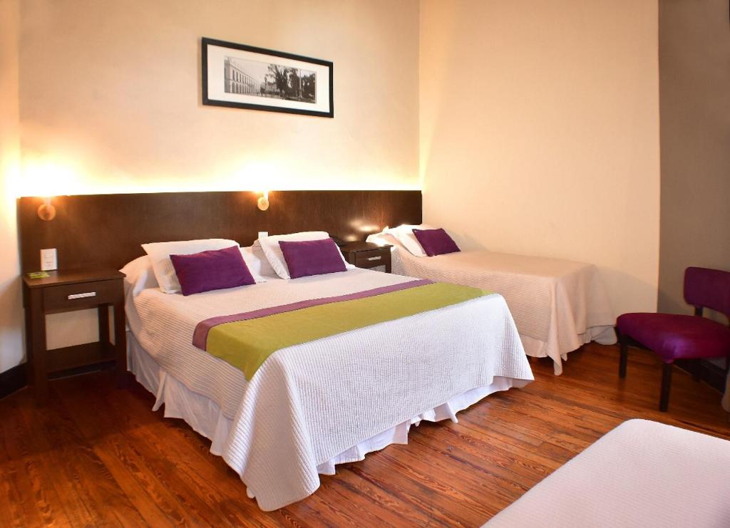a hotel room with two beds with purple and green pillows at Gran Rex Hotel in Córdoba