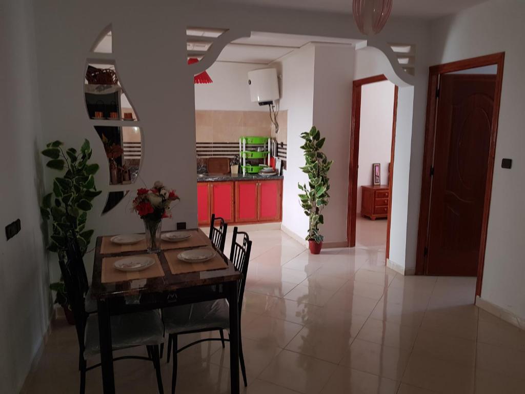 a dining room with a table and chairs and a kitchen at joli appartement 4 chambres in Oujda