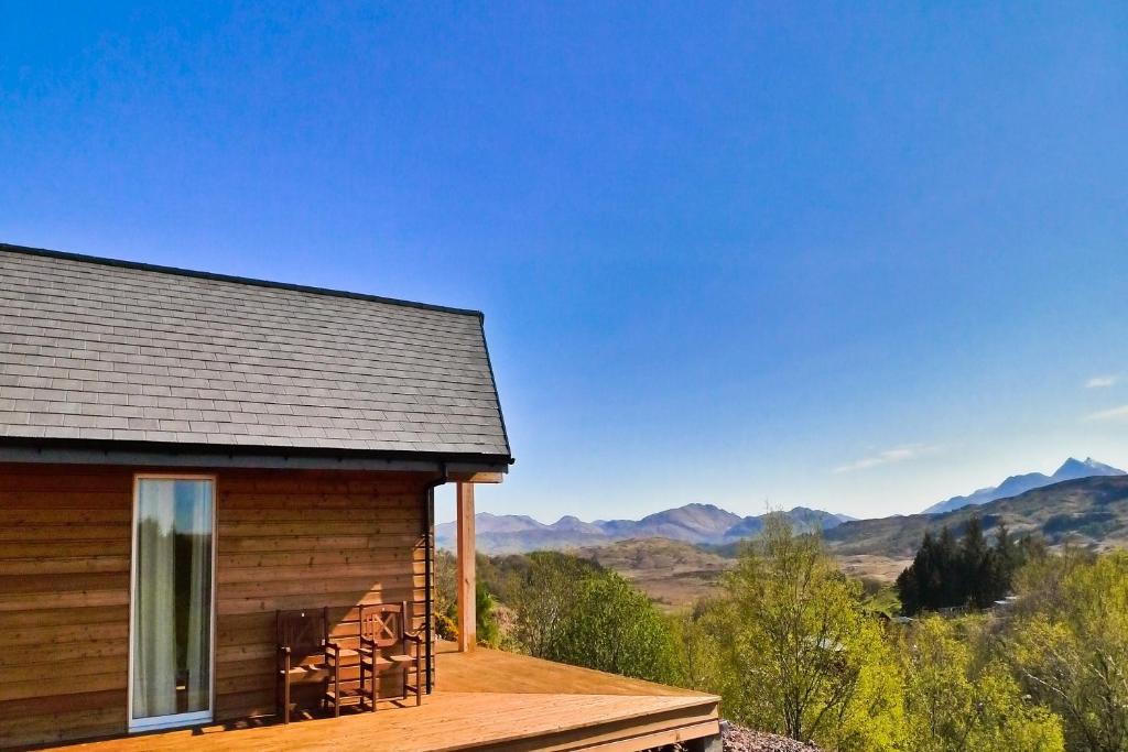 een hut met een terras met uitzicht op de bergen bij Aspen Lodge in Oban