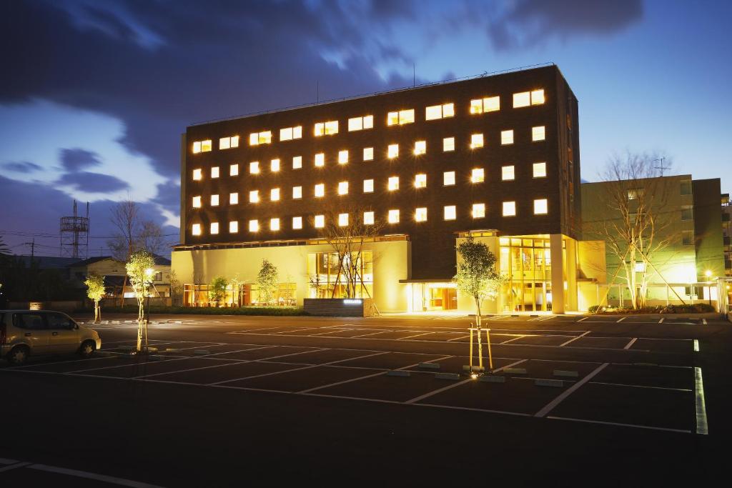 a large building with lights in a parking lot at Takanokono Hotel in Matsuyama