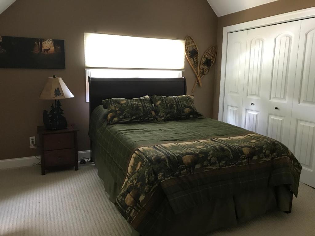 a bedroom with a bed with a green bedspread and a window at Lamp Lighter Mountain Inn in Zirconia