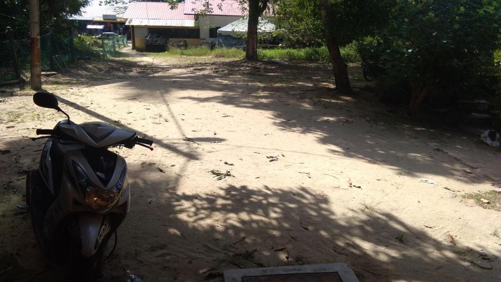 ein Motorrad, das auf einer unbefestigten Straße geparkt ist in der Unterkunft Nipahmas Chalet in Pulau Pangkor