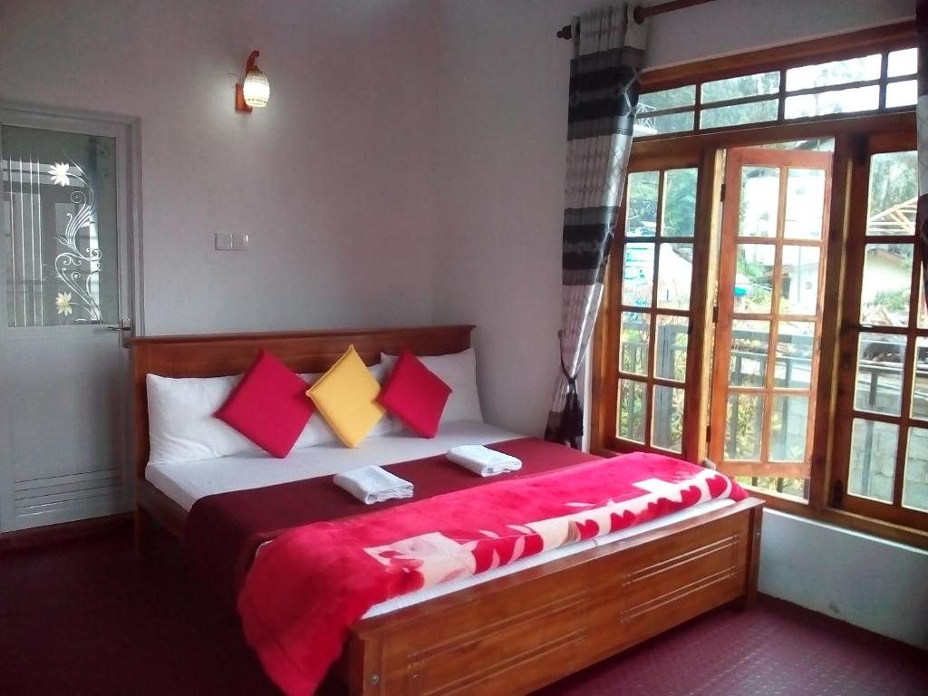 a bedroom with a bed with red and yellow pillows at King's Lodge in Nuwara Eliya