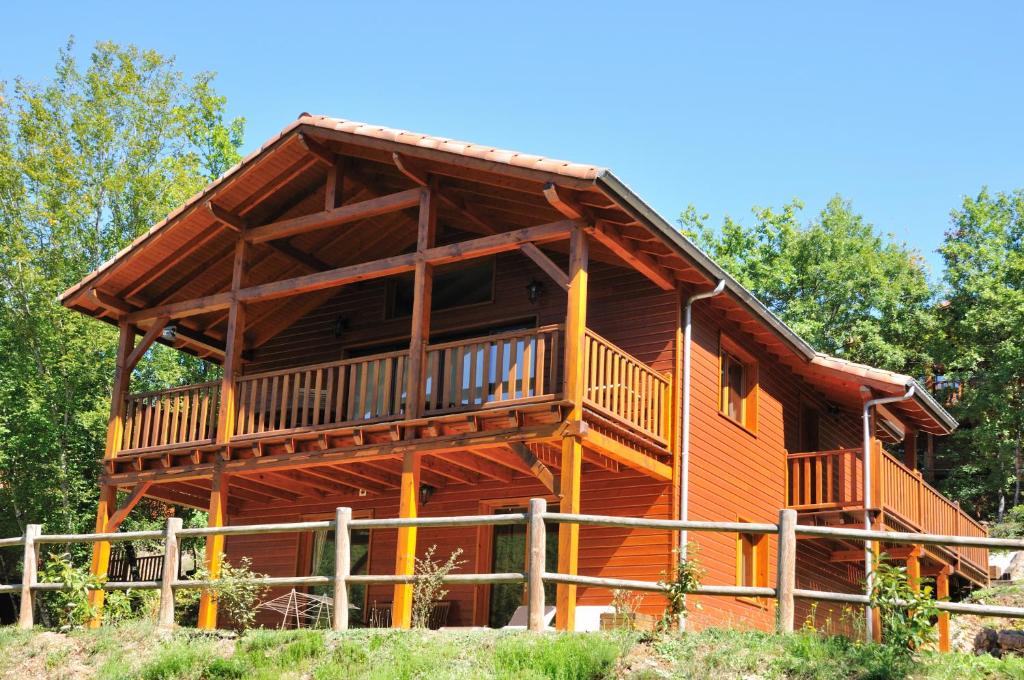a large log cabin with a balcony on a house at Résidence Souillac Golf & Country Club in Lachapelle-Auzac