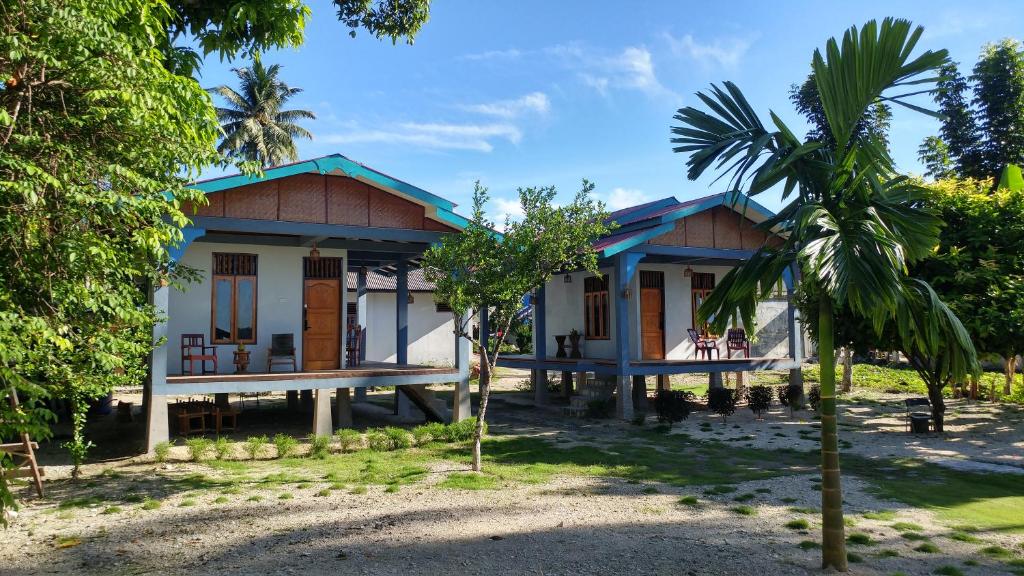 a house with a palm tree in front of it at New Raya - Nias Beach Bungalows in Lagudri