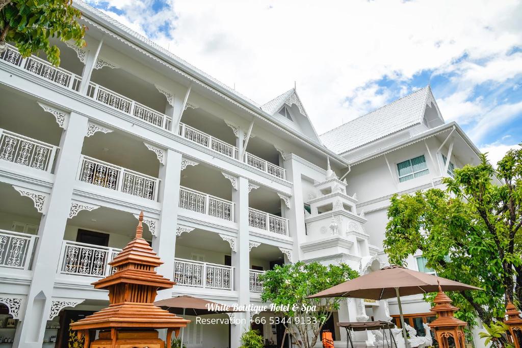 ein großes weißes Gebäude mit einem Schirm davor in der Unterkunft White Boutique Hotel and Spa in Chiang Mai