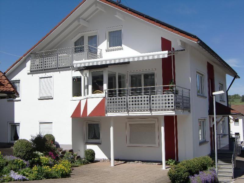 a white and red house with a balcony at Haus-Fechtig-Wohnung-Typ-C in Bonndorf im Schwarzwald