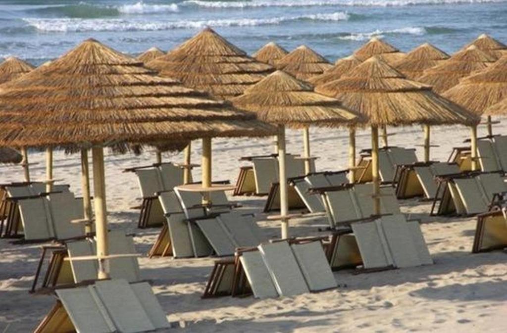 un montón de sillas y sombrillas en una playa en Collins Apartments en Castellaneta Marina 