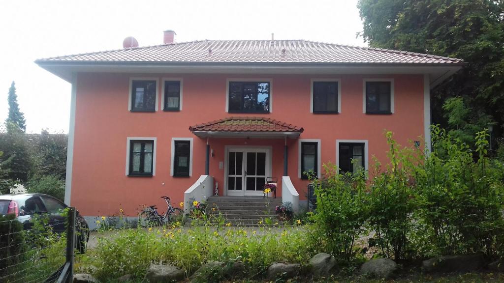 een groot oranje huis met de voordeur open bij Fewo 1 Waren Müritz - Haus Buchen am Tiefwarensee - 1 Zi in Waren