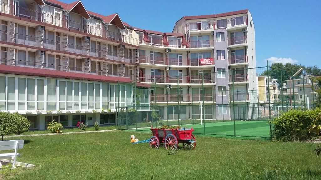 un gran edificio con una pista de tenis y un vagón rojo en Club Hotel Vedren, en Kranevo