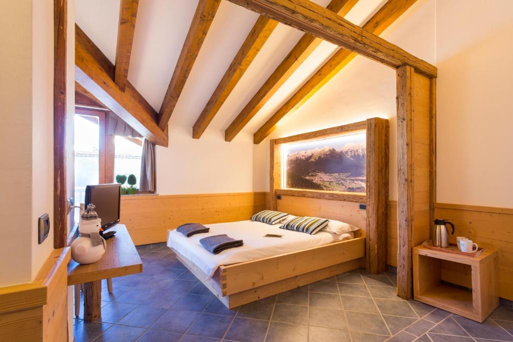 um quarto com uma cama num quarto com tectos em madeira em Hotel Angelo em Andalo