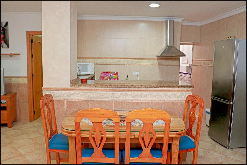 コニル・デ・ラ・フロンテーラにあるApartamento Conil Ceutaのキッチン(テーブル、椅子、冷蔵庫付)