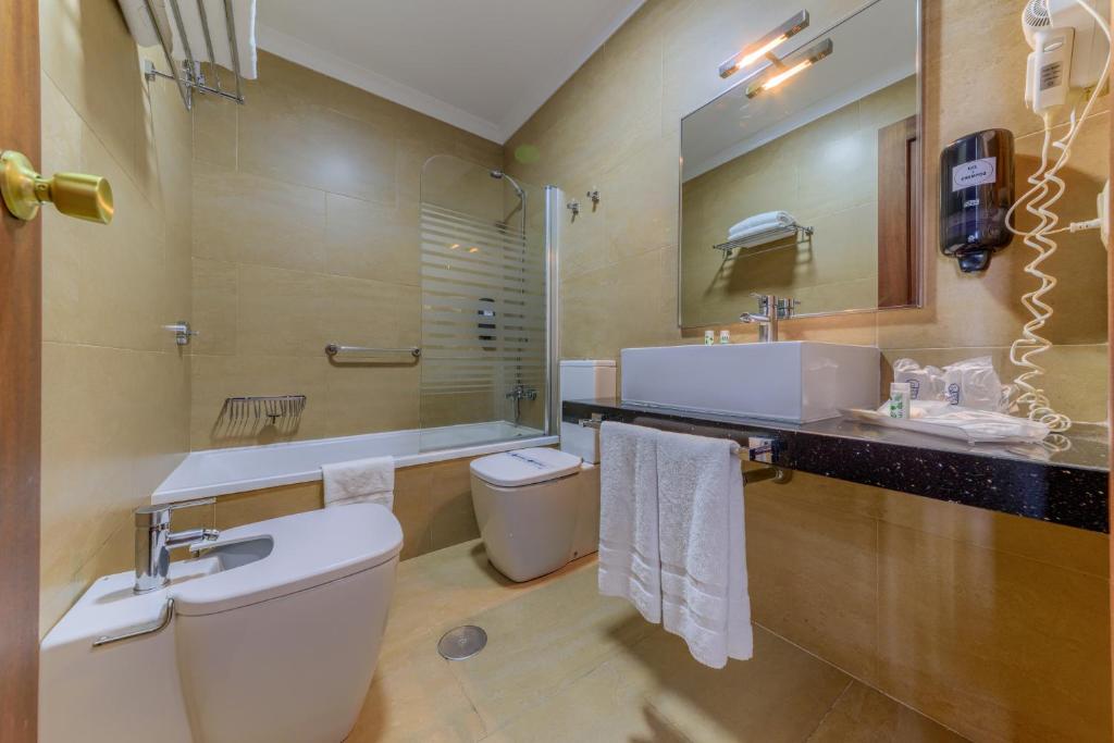 a bathroom with a toilet a sink and a bathtub at Hotel Playa de Regla in Chipiona