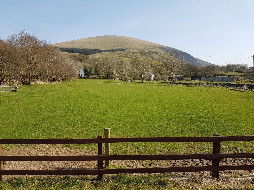 a fence in a field with a hill in the background at Buarth Wern in Caernarfon