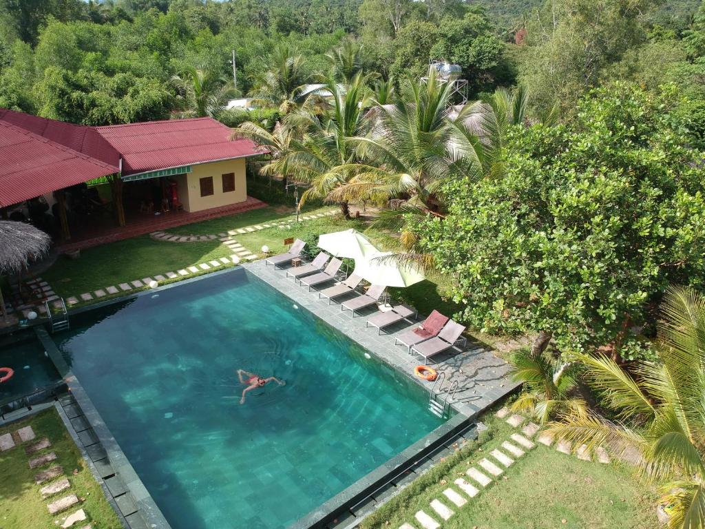 an overhead view of a swimming pool with chairs and a house at Ninila Fruit Farm Bungalow in Phu Quoc