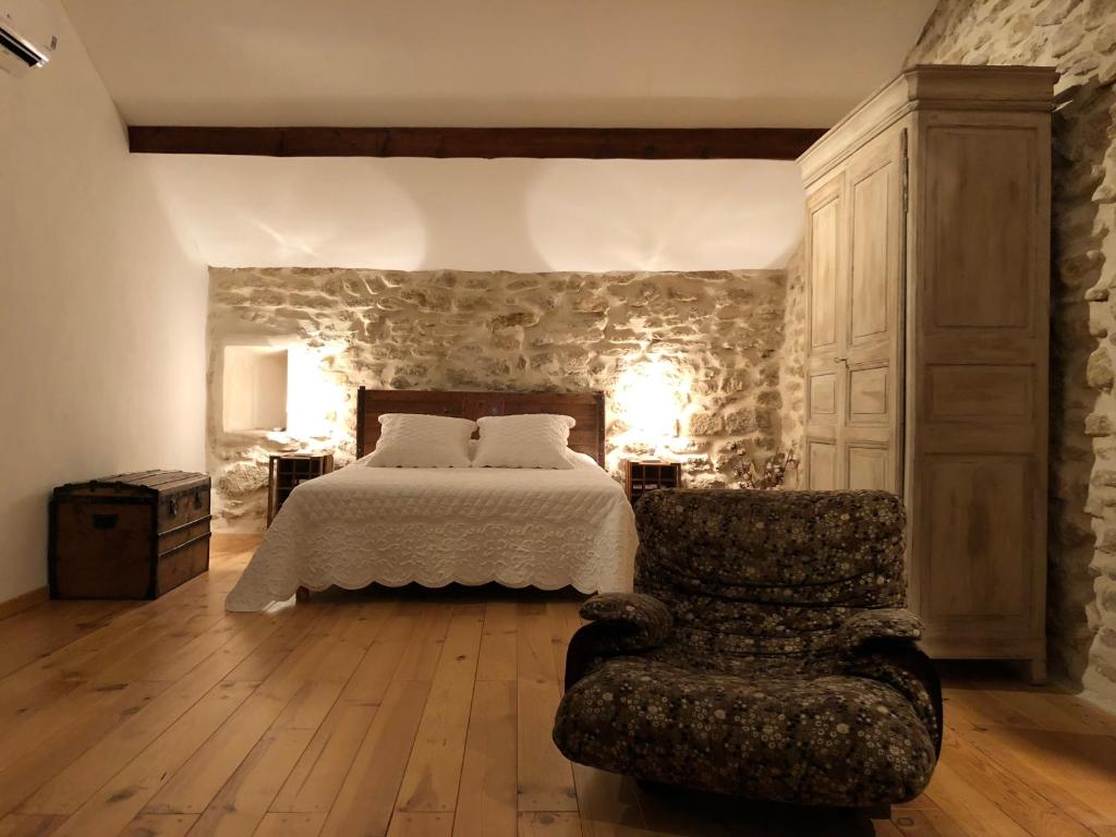 a bedroom with a bed and a chair at B&B - Le Vieux Figuier in Vacqueyras