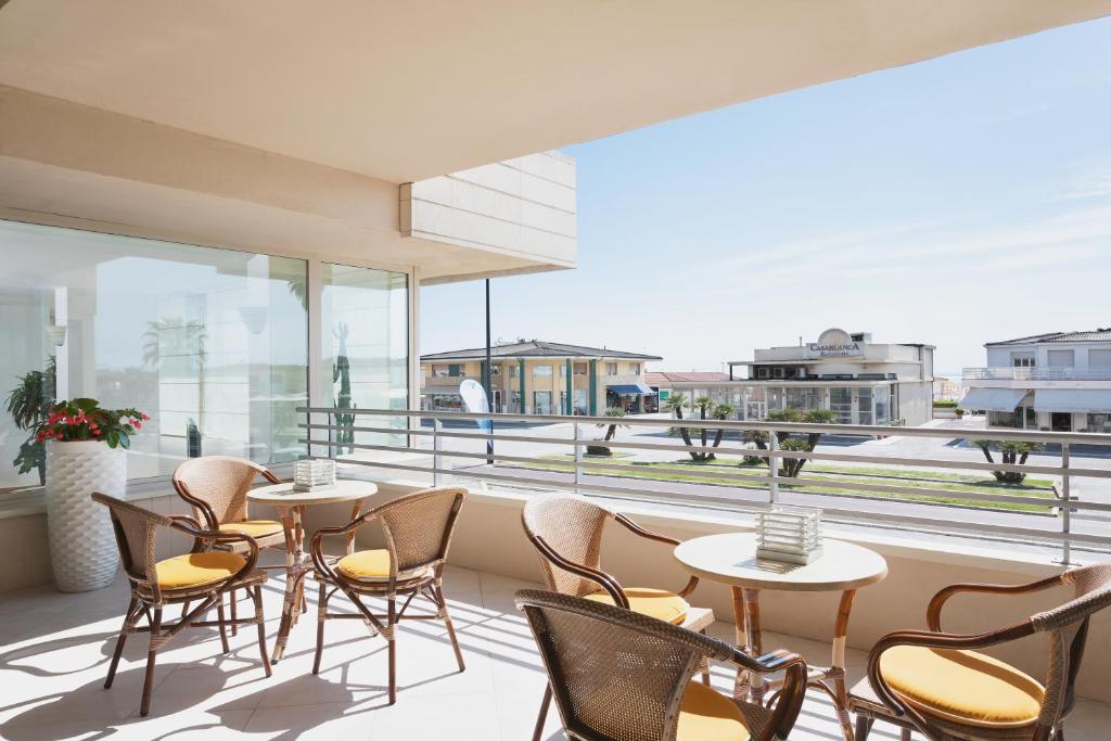 a patio with tables and chairs on a balcony at Hotel Sina Astor in Viareggio