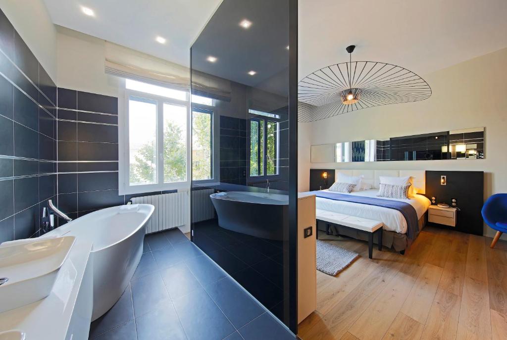a bathroom with a bed and a bath tub and a bedroom at Negrecoste Hôtel & Spa in Aix-en-Provence