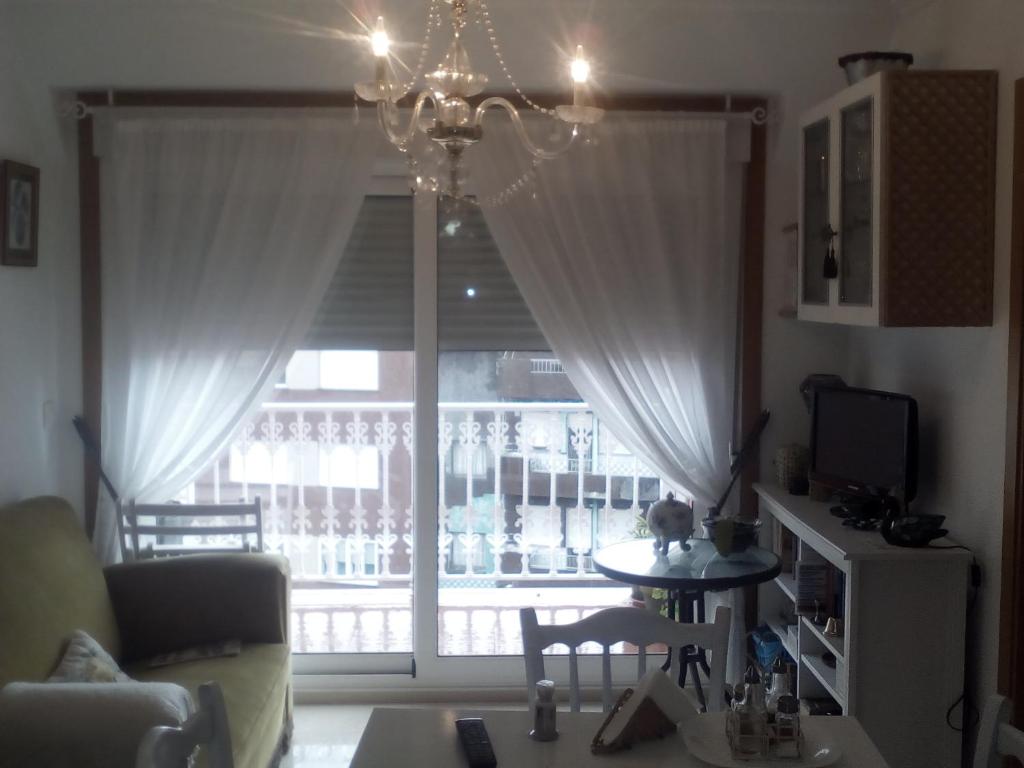 sala de estar con lámpara de araña y ventana grande en Apartamento de playa, en Boiro