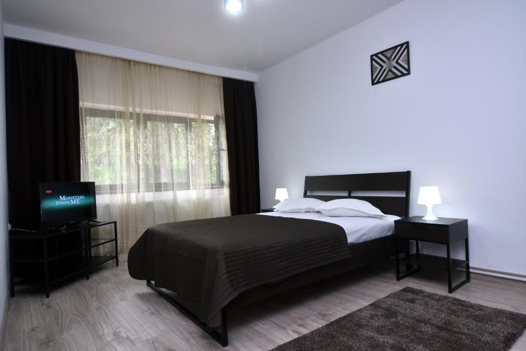 - une chambre avec un grand lit et une télévision dans l'établissement Residence SINAIA Apartments, à Sinaia