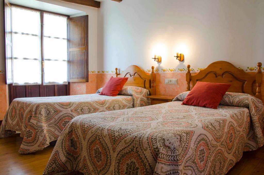 Aria的住宿－Casa Rural ERTEIKOA - Selva de Irati，一间卧室配有两张带红色枕头的床。