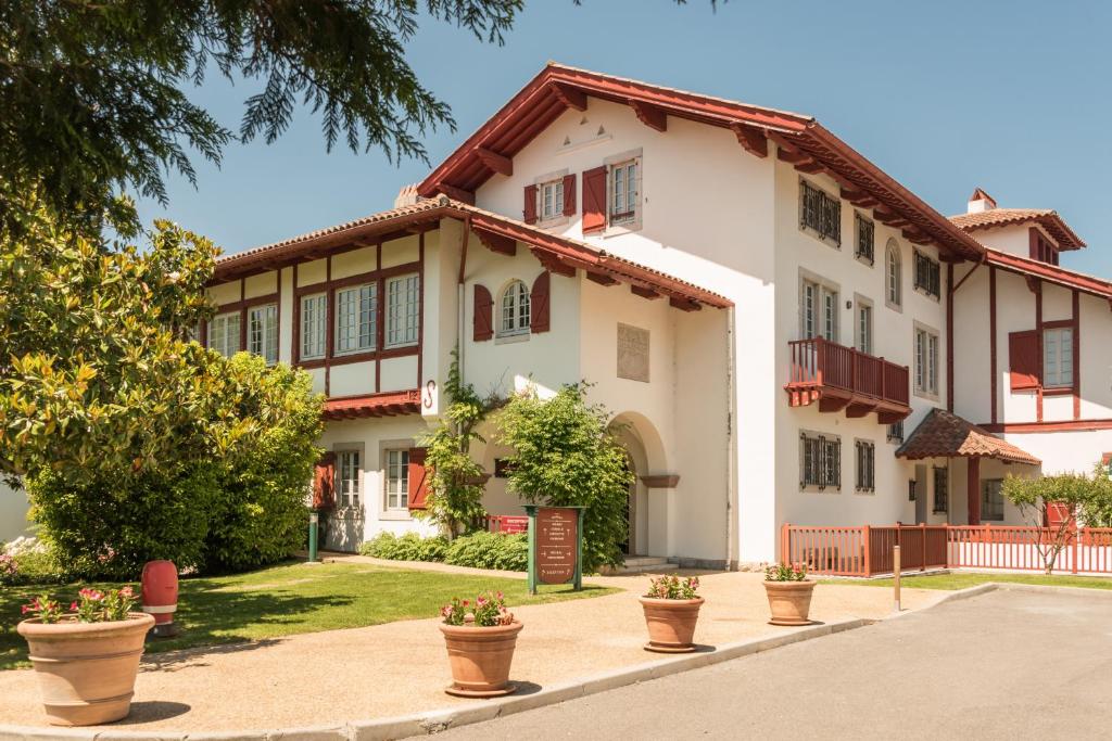 une grande maison blanche avec des plantes en pot devant elle dans l'établissement Résidence Pierre & Vacances La Villa Maldagora, à Ciboure