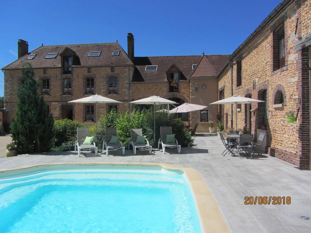 a swimming pool in front of a building with chairs and umbrellas at TESS Villa Fournadin in Fournaudin