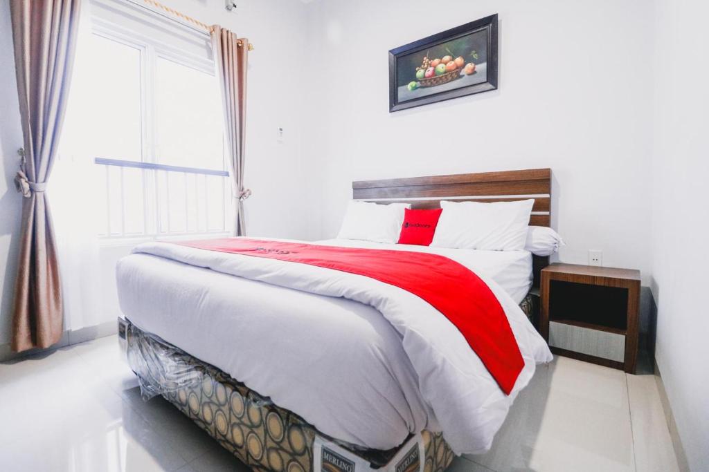 a bedroom with a red and white bed and a window at RedDoorz near Hermes Place Polonia Medan in Medan