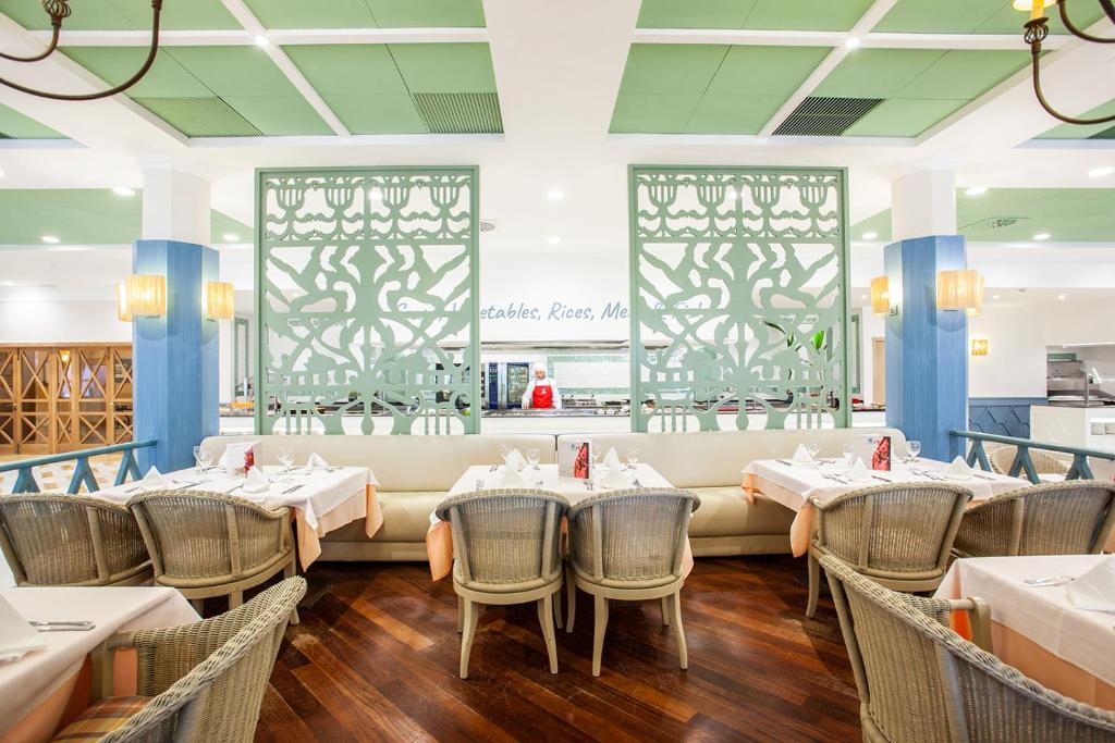a restaurant with tables and chairs and a couch at Grupotel Playa Club in Son Xoriguer