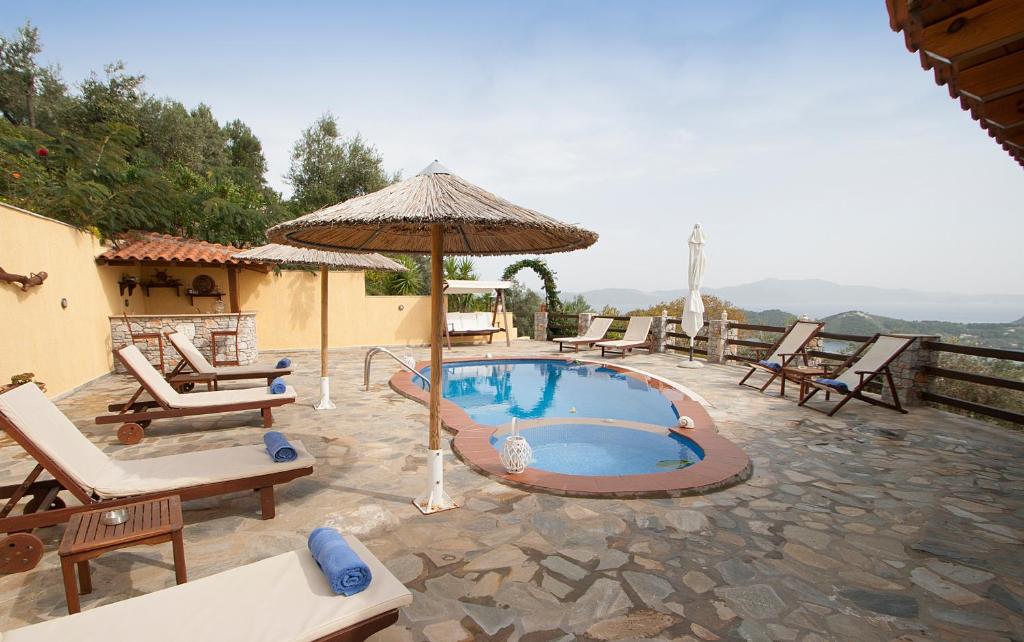 a pool with chairs and an umbrella on a patio at Villa Fotini in Skiathos