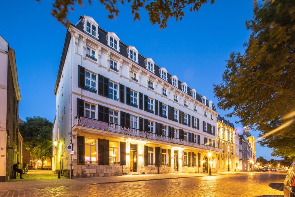 a large white building on a street at night at Hotel Monastère Maastricht in Maastricht