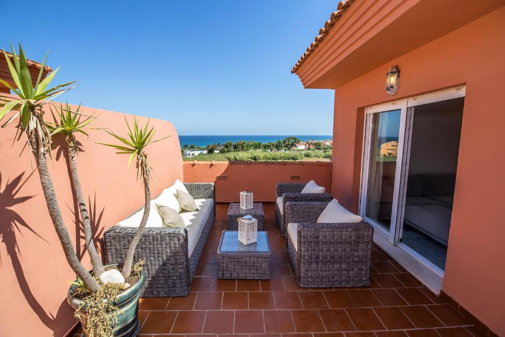 un patio con sillas de mimbre, una mesa y palmeras en Los Hidalgos Penthouse, en Manilva