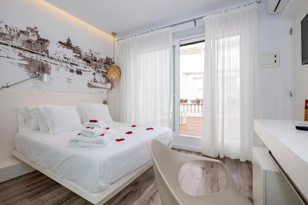 a white bedroom with a bed with roses on it at Hotel Abril 37 in Ciutadella