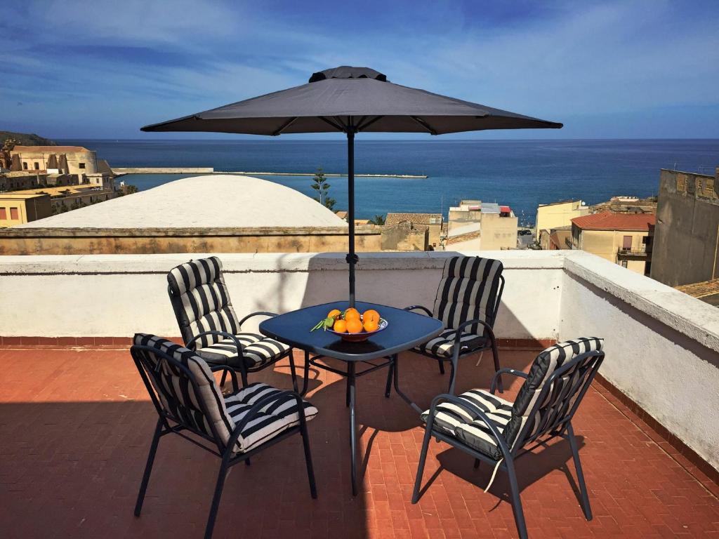 a table with chairs and an umbrella on a balcony at Casa Vacanza nel cuore di Castellammare del golfo in Castellammare del Golfo