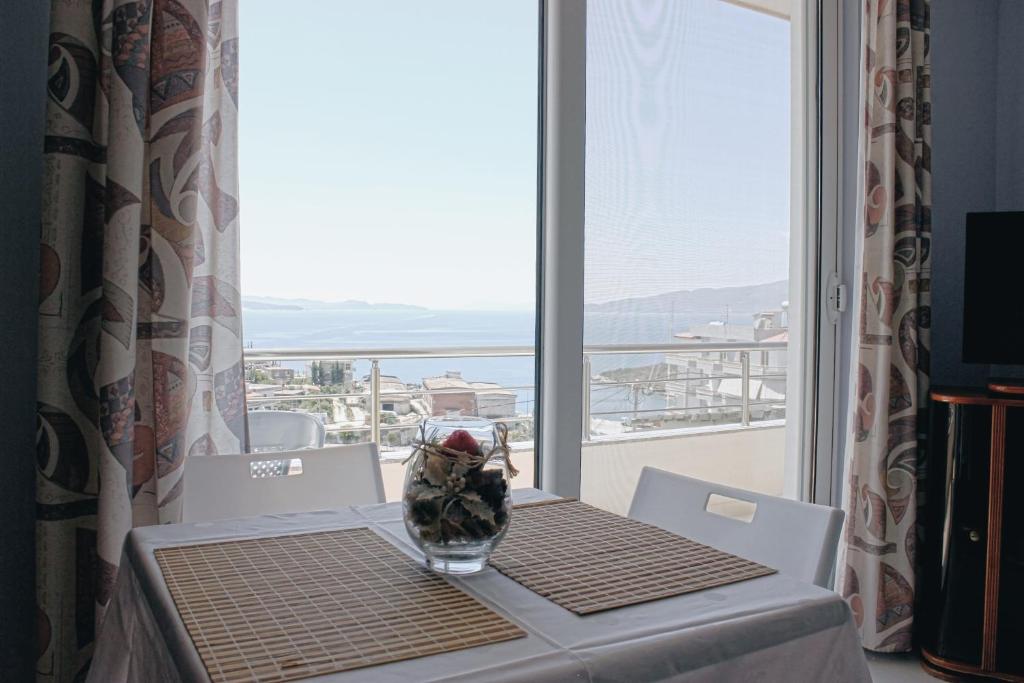 a table with a vase on a table with a window at Elti Apartment in Sarandë