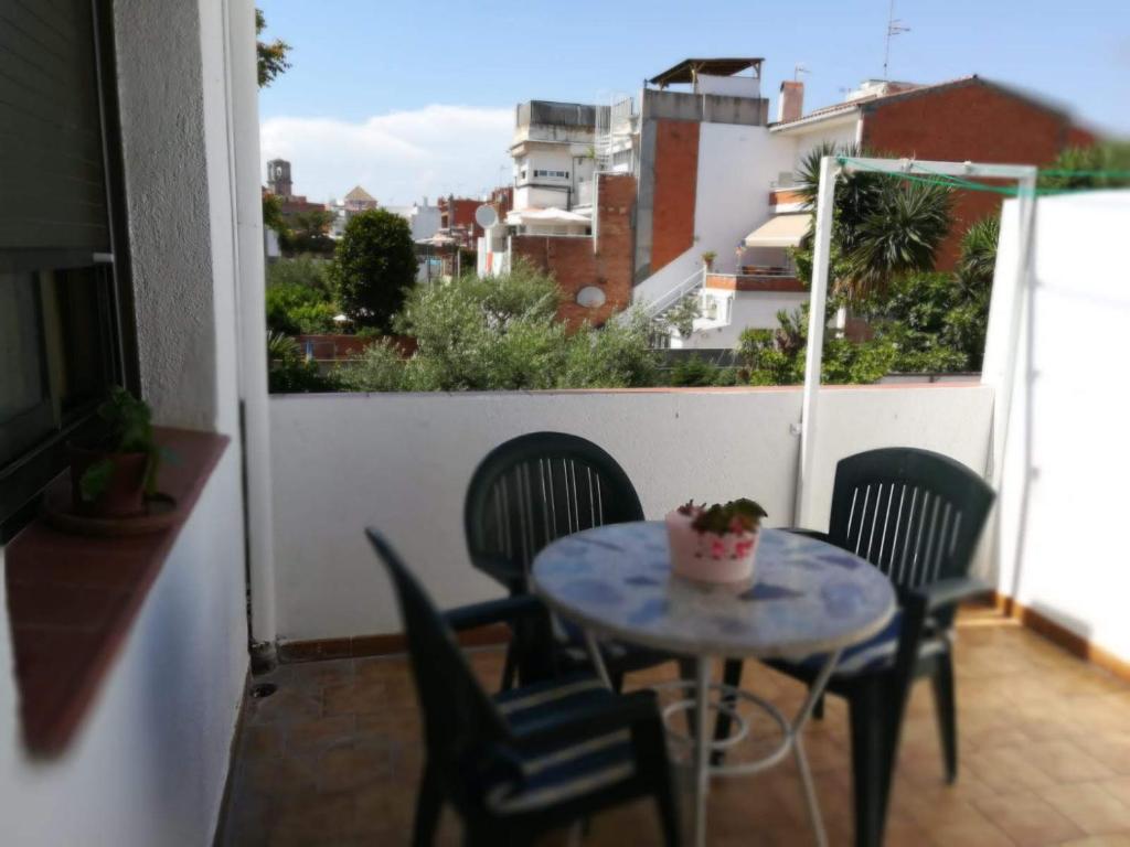 a small table and chairs on a balcony with a view at Encantador apartamento cerca de la playa in Malgrat de Mar