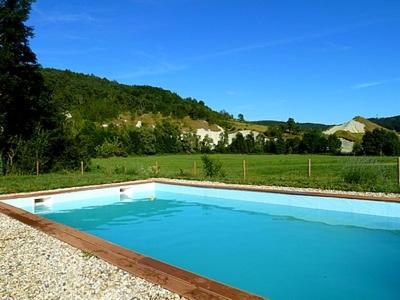 a large blue swimming pool with a hill in the background at Alcove Du Velay in Rochelimagne