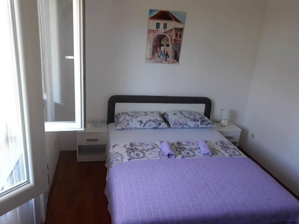 - une chambre avec un lit doté de draps violets et une fenêtre dans l'établissement Apartman Anja, à Trebinje