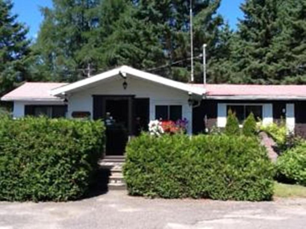 une maison blanche avec une terrasse couverte et des buissons dans l'établissement Auberge Mountain View Inn, à Mont-Tremblant