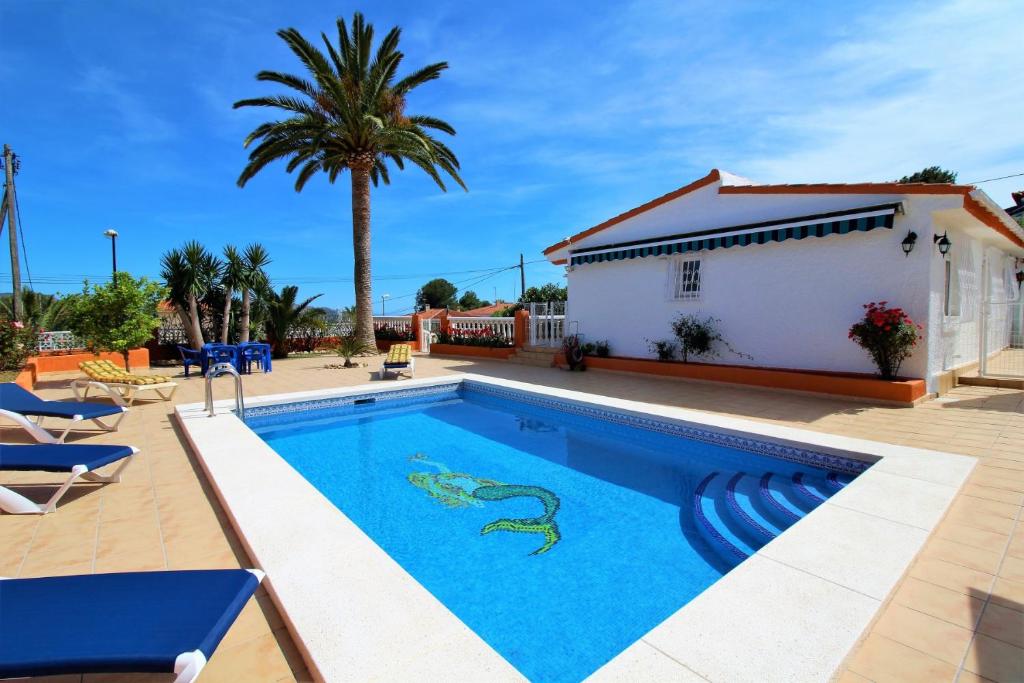 einen Pool mit einem Haus und Palmen in der Unterkunft Villa Mediterránea in L’Alfàs del Pi
