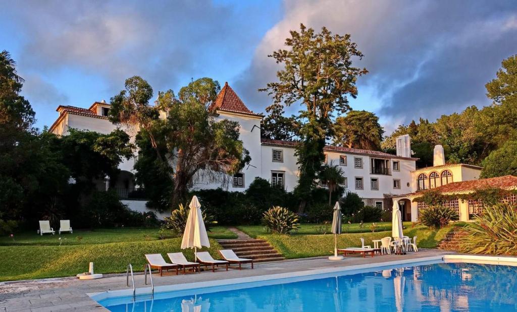 une grande maison blanche avec une piscine en face de celle-ci dans l'établissement Quinta de Sao Thiago, à Sintra