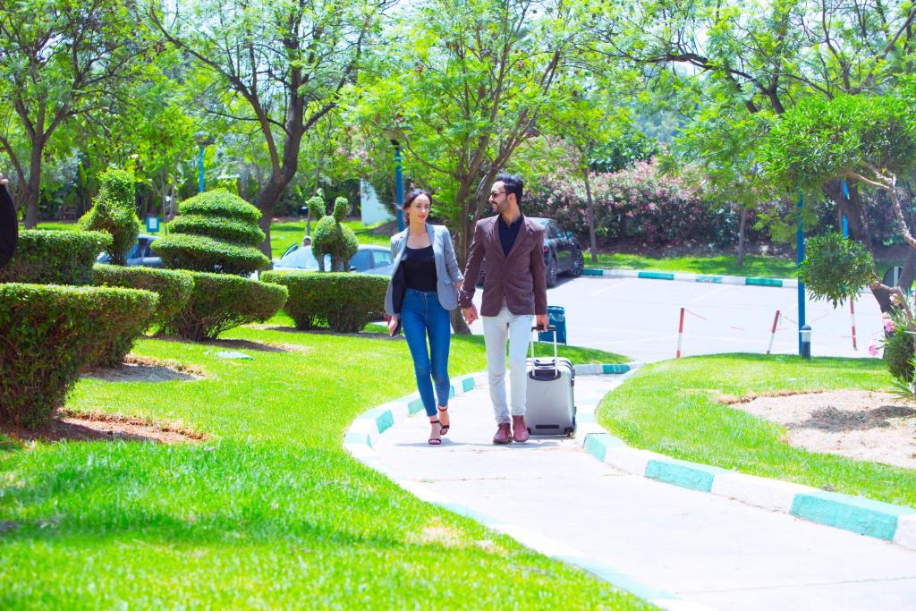 un hombre y una mujer caminando por una acera con una maleta en Ibis Meknes en Meknès