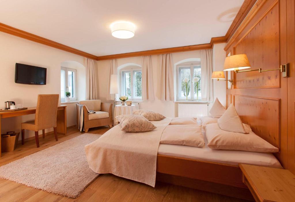 a bedroom with a large bed with a desk and a chair at Hotel Fischerhaus in Starnberg