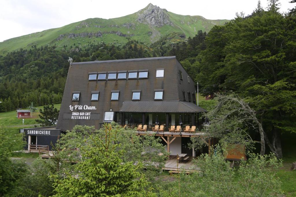 un bâtiment avec une montagne en arrière-plan dans l'établissement Gîte-Hôtel Le P'tit Cham, à Le Mont-Dore