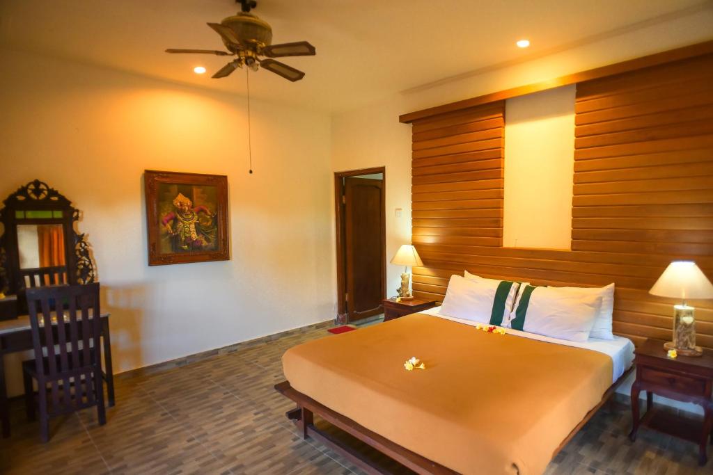 a bedroom with a large bed with a wooden headboard at Ina Inn in Ubud