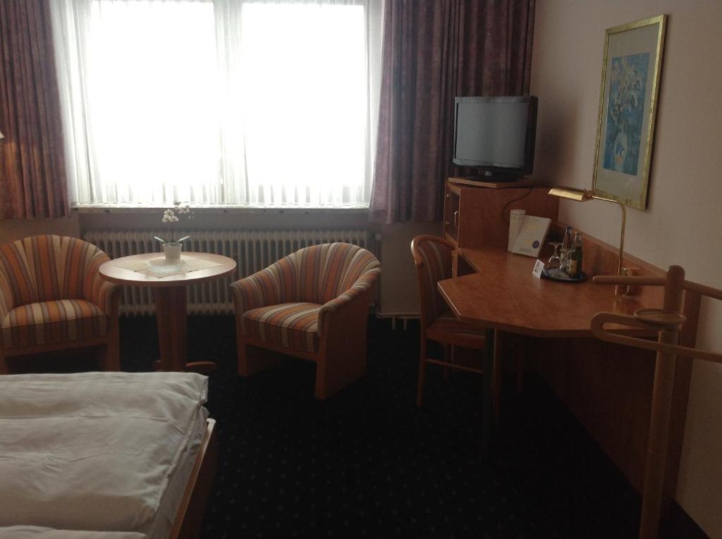 ein Hotelzimmer mit einem Bett, einem Tisch und Stühlen in der Unterkunft Witt's Gasthof in Krummbek