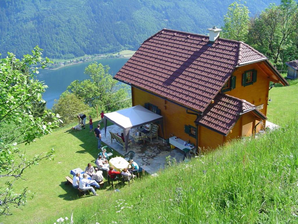 een groep mensen die buiten een huis zitten bij Almchalet Orter in Deutschberg