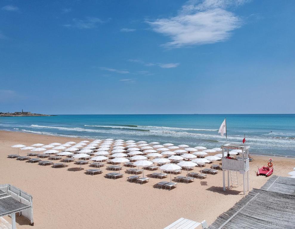 a beach with chairs and umbrellas and the ocean at VOI Marsa Siclà Essentia in Sampieri